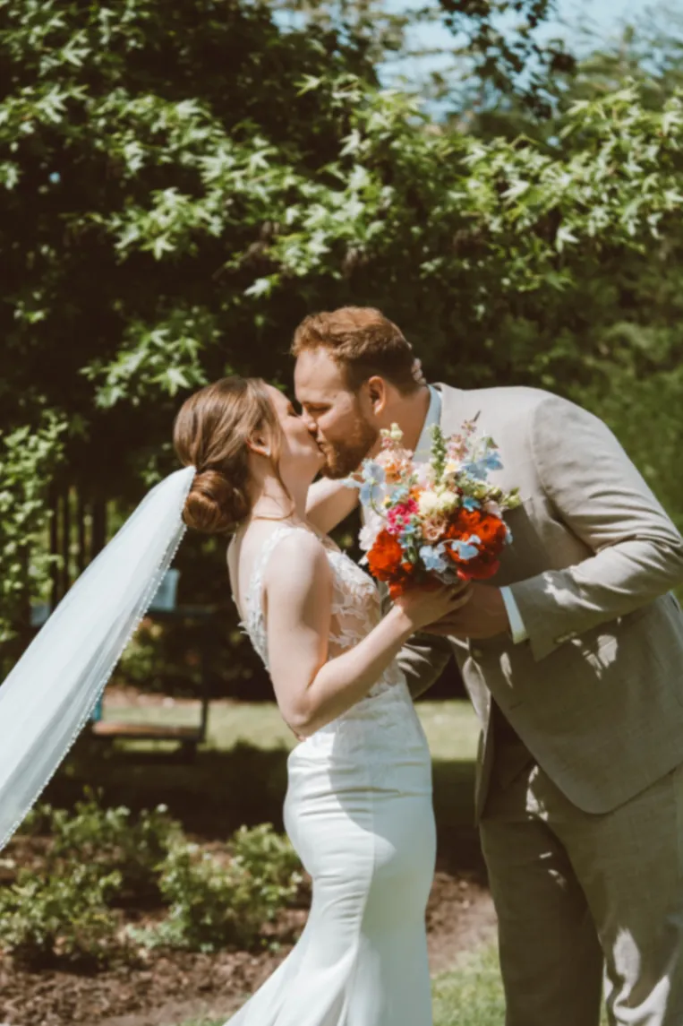 Huwelijksfotografie bruidspaar kussend in tuin – A Fond Studios